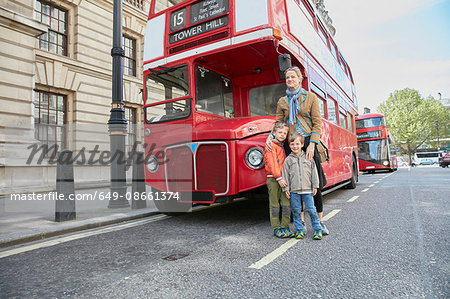 Mother and sons in front of red double decker bus