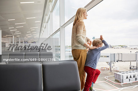 Mother and sons in departure lounge looking out of window