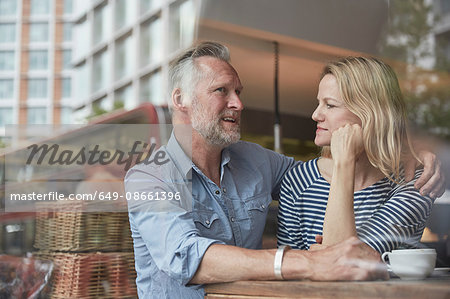 View through window of mature couple in coffee shop chatting