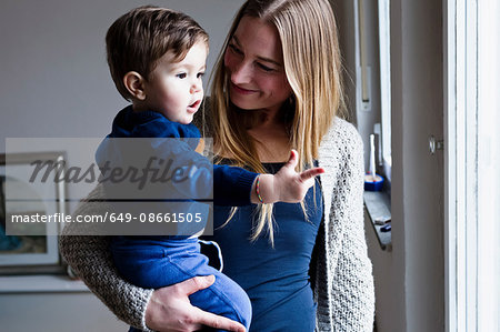 Mid adult woman carrying baby son, pointing