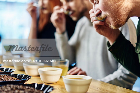 Team tasting bowls of coffee at coffee shop tasting