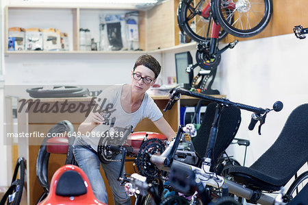 Woman in bicycle workshop checking pedal on recumbent bicycle