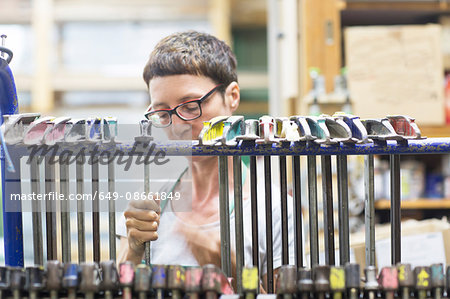 View through hanging clamp tools of woman in workshop