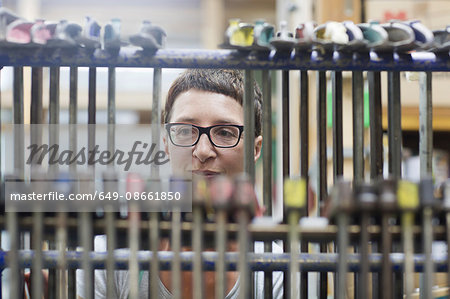 View through hanging clamp tools of woman in workshop