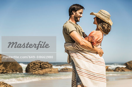 Romantic couple wrapped in blanket face to face on beach, Cape Town, South Africa