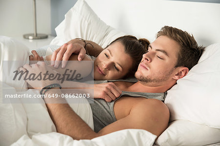 Young couple lying in bed hugging