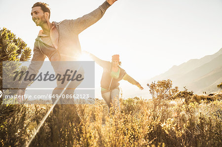 Couple running in field, arms open