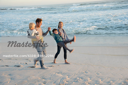 Happy young family having fun on the beach at sunset