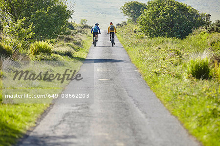 Rear view of cyclists cycling on rural road