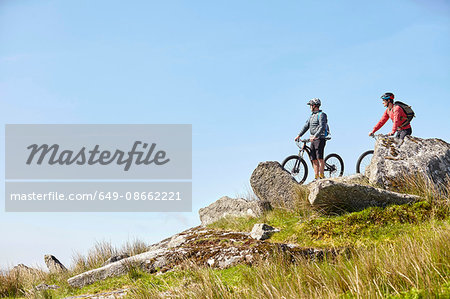Cyclists on bicycles on rocky outcrop looking away
