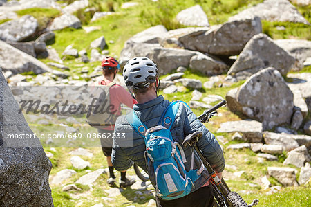 Cyclists carrying bicycles on rocky outcrop