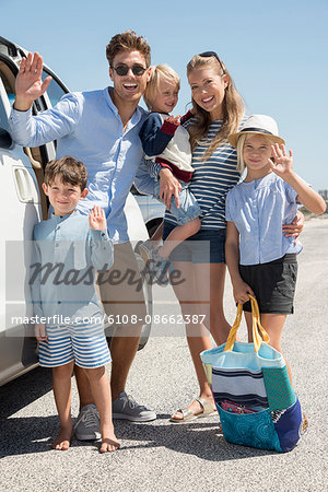 Happy young family standing by car for vacation