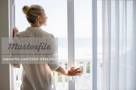 Young woman standing by window at home