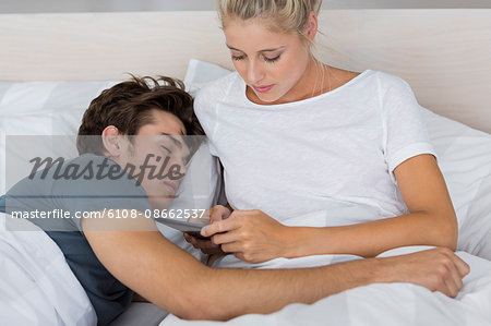 Young woman using a digital tablet with her boyfriend sleeping near her