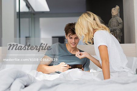 Couple using a digital tablet on the bed