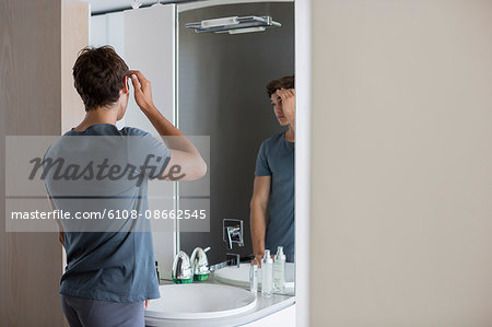 Young man checking his hair in mirror