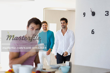 Happy friends looking at young man drinking coffee