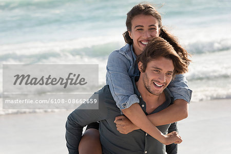 Happy young woman riding piggyback on her friend shoulder