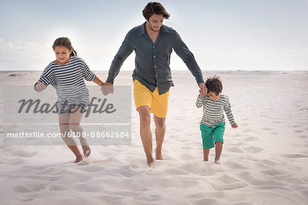 Happy father running with his children on beach
