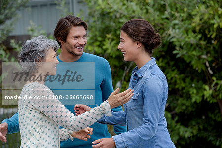 Happy mature woman meet with young couple outside