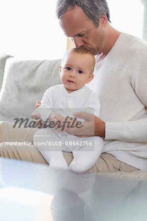 Father kissing his cute baby daughter in living room