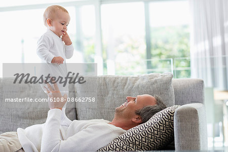 Happy father playing with his cute baby daughter at home