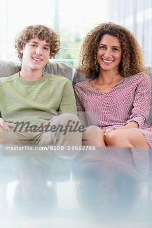 Portrait of happy mother and son sitting on couch in living room