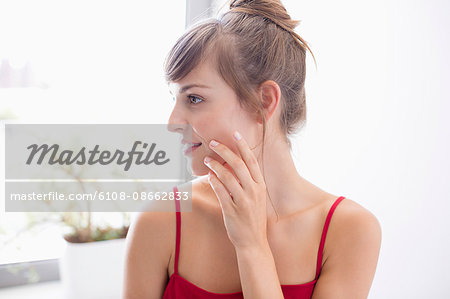 Beautiful woman applying moisturizer on face in bathroom