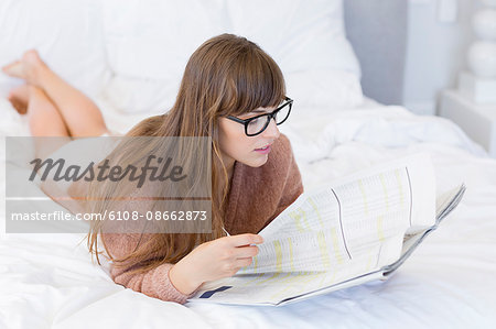 Woman reading a newspaper on the bed
