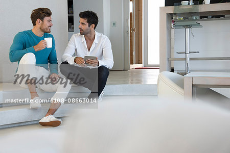 Happy male friends using a digital tablet at home