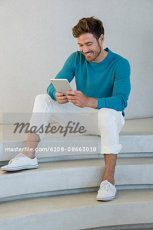 Happy young man using a digital tablet at home