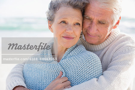 Active senior man embracing his wife from behind on the beach