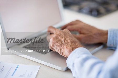 Senior man paying bills online on laptop