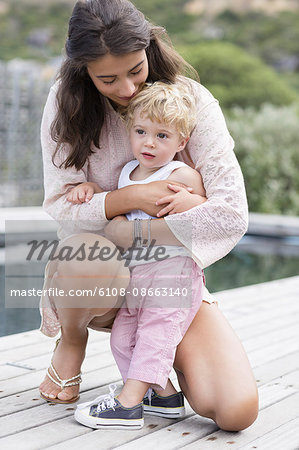 Happy mother playing with son at poolside