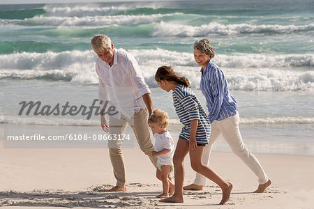 Happy grandparents walking with grandchildren on beach