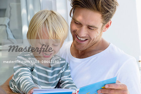 Happy father and son reading a book