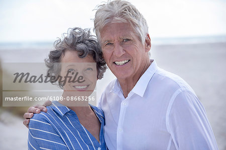 Portrait of happy senior couple standing on beach