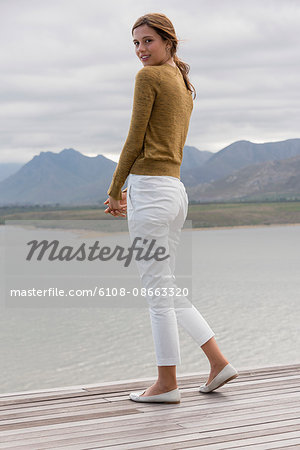 Portrait of happy woman standing on deck at lakeshore