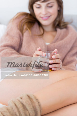 Happy woman with cup of herbal tea in bed