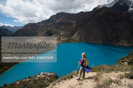 A trekker stands above the turquoise blue Phoksundo Lake in the Dolpa region, Himalayas, Nepal, Asia