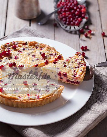 White chocolate cheesecake tart with cranberries on a white plate Wooden rustic background