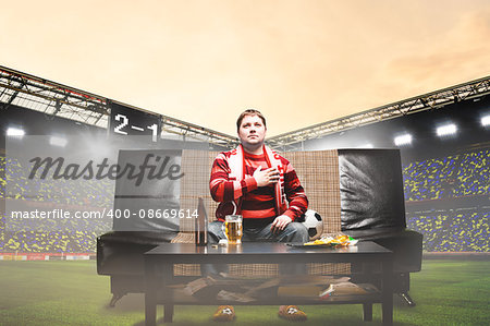 happy soccer or football fan with hand on heart on sofa at stadium