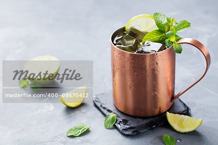 Cold Moscow Mules cocktail with ginger beer, vodka, lime Grey stone background. Copy space