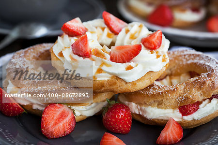 Cream puff rings (choux pastry) decorated with fresh strawberry and caramel sauce