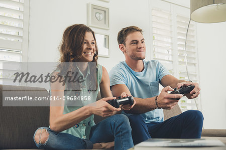 Couple on sofa using video game controller smiling