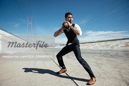 Businessman playing american football on Los Angeles river, California, USA