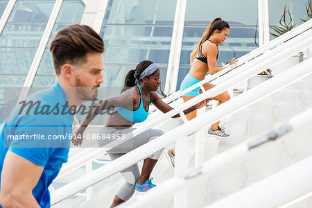 Side view of man and two women training, running up stairway at sport facility, downtown San Diego, California, USA