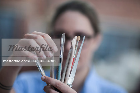 Close up of female potters hand selecting tool in workshop