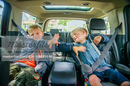 Twin brothers sitting in back of vehicle, fighting