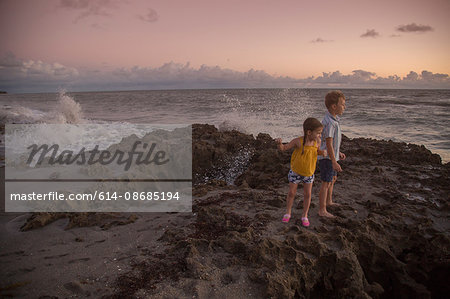 Girl and brother looking out from beach at sunrise, Blowing Rocks Preserve, Jupiter Island, Florida, USA